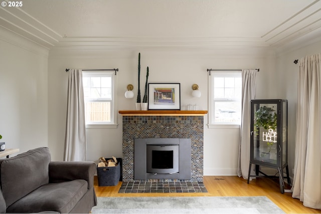 living room featuring crown molding, a healthy amount of sunlight, a fireplace, and light hardwood / wood-style floors