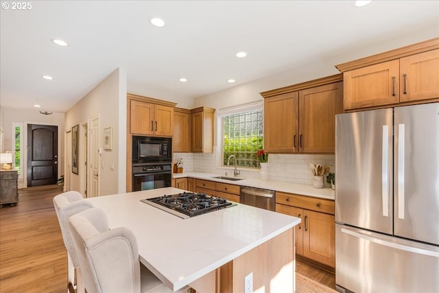 kitchen with black appliances, a sink, recessed lighting, light countertops, and backsplash