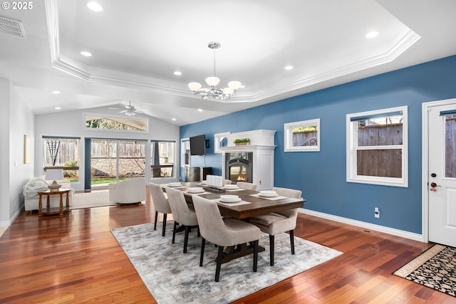 dining room with visible vents, baseboards, a premium fireplace, and wood finished floors