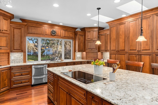 kitchen featuring a sink, a skylight, black electric stovetop, and brown cabinets