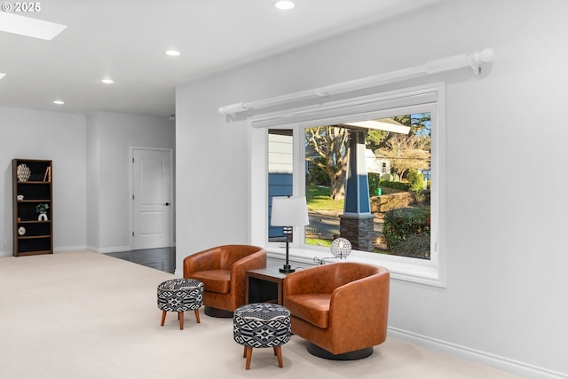 living area featuring carpet floors, baseboards, recessed lighting, and a skylight