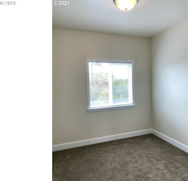 carpeted empty room featuring baseboards and a textured ceiling