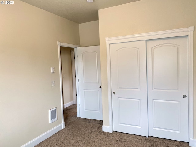 unfurnished bedroom featuring dark carpet, baseboards, and a closet