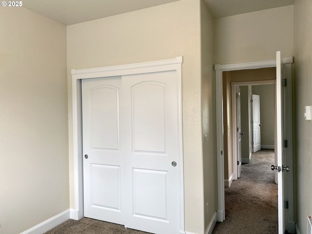 unfurnished bedroom featuring dark carpet, baseboards, and a closet
