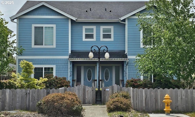 view of front of house featuring fence and roof with shingles