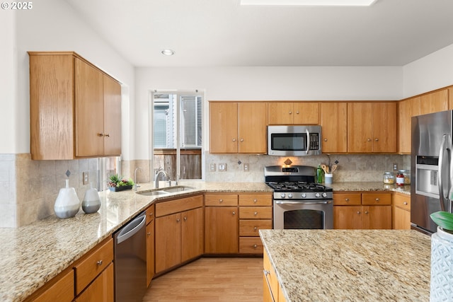 kitchen featuring stainless steel appliances, sink, backsplash, and light hardwood / wood-style flooring