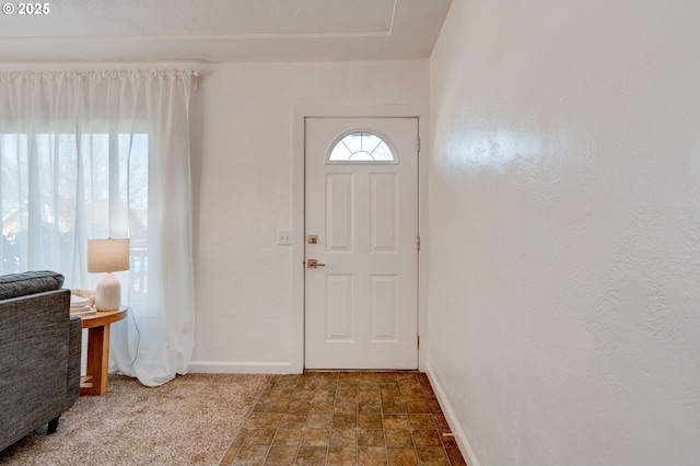 foyer entrance with stone finish floor and baseboards