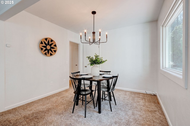 dining room featuring light carpet, baseboards, and an inviting chandelier