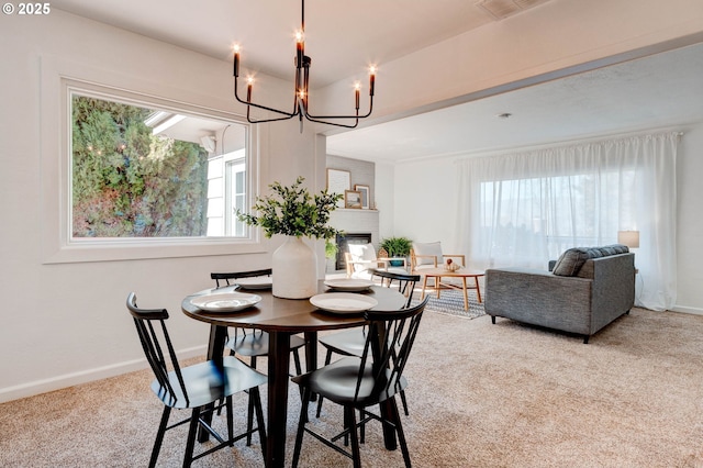 carpeted dining area featuring a fireplace, baseboards, and a notable chandelier