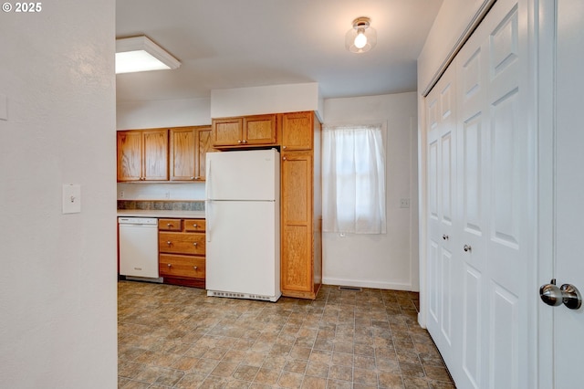 kitchen featuring white appliances, brown cabinets, stone finish floor, and baseboards