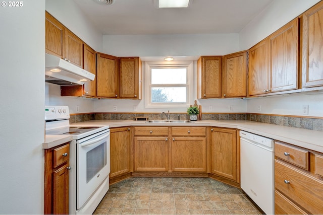 kitchen with brown cabinets, white appliances, a sink, and under cabinet range hood