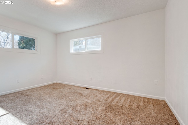 unfurnished room featuring visible vents, a textured ceiling, baseboards, and carpet flooring