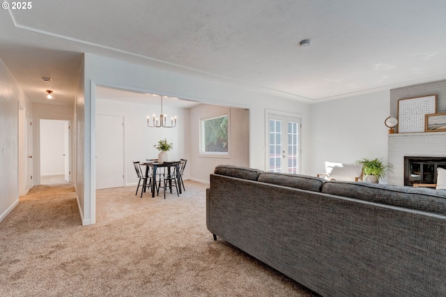 carpeted living room with a brick fireplace, baseboards, and an inviting chandelier