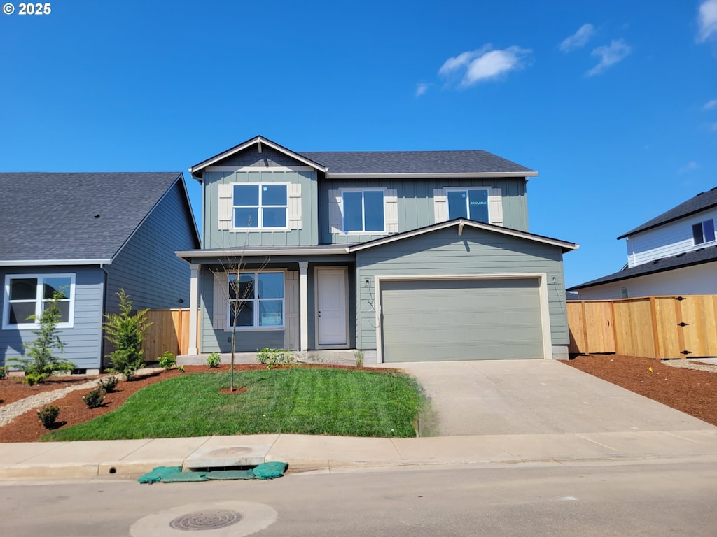 traditional-style home with driveway, board and batten siding, an attached garage, fence, and a front lawn