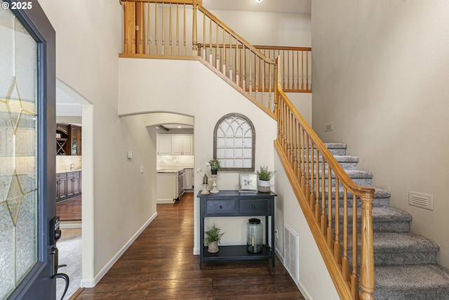 stairs featuring a towering ceiling and wood-type flooring