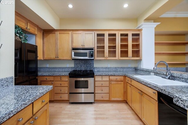 kitchen with recessed lighting, glass insert cabinets, a sink, light wood-type flooring, and black appliances