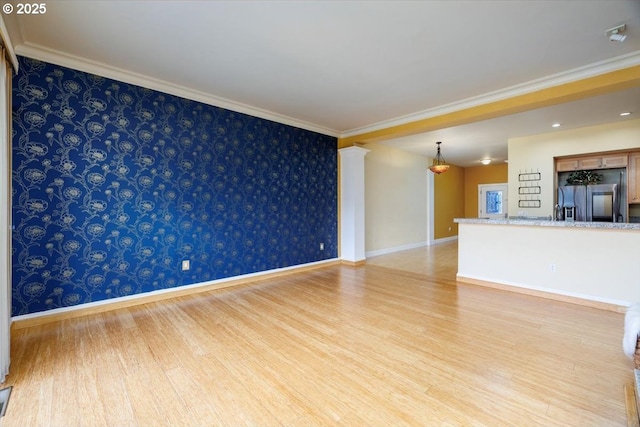 empty room with baseboards, crown molding, wood finished floors, and wallpapered walls