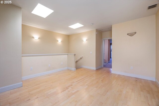 unfurnished room featuring visible vents, light wood-style flooring, and baseboards