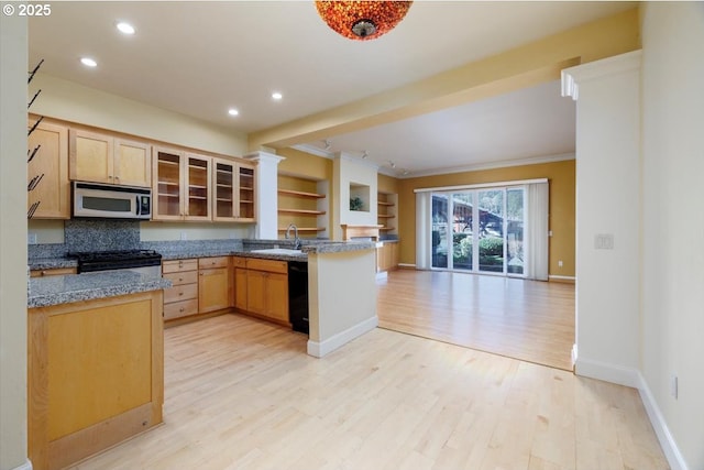 kitchen with gas range oven, stainless steel microwave, open floor plan, a sink, and a peninsula