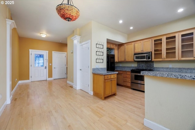 kitchen with light wood-type flooring, baseboards, glass insert cabinets, and stainless steel appliances