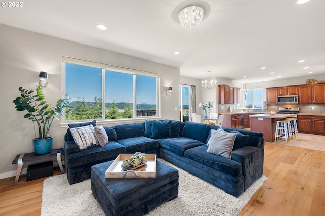living area with light wood-style floors, baseboards, recessed lighting, and a chandelier