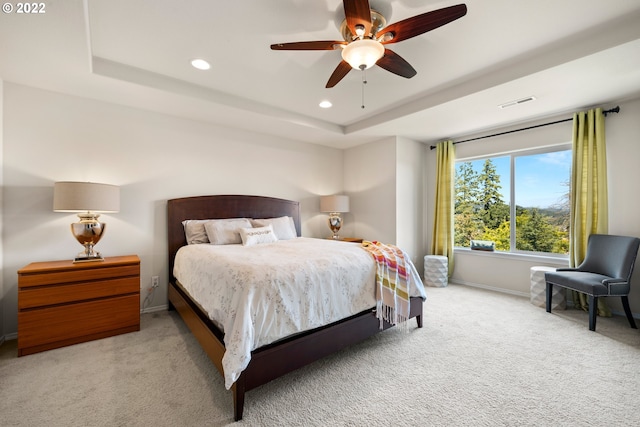 carpeted bedroom featuring visible vents, baseboards, recessed lighting, a raised ceiling, and a ceiling fan