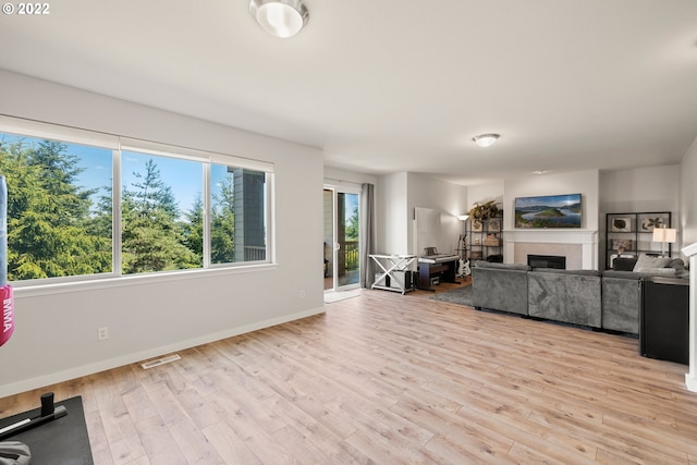 living room with light wood-style floors, baseboards, a fireplace, and visible vents