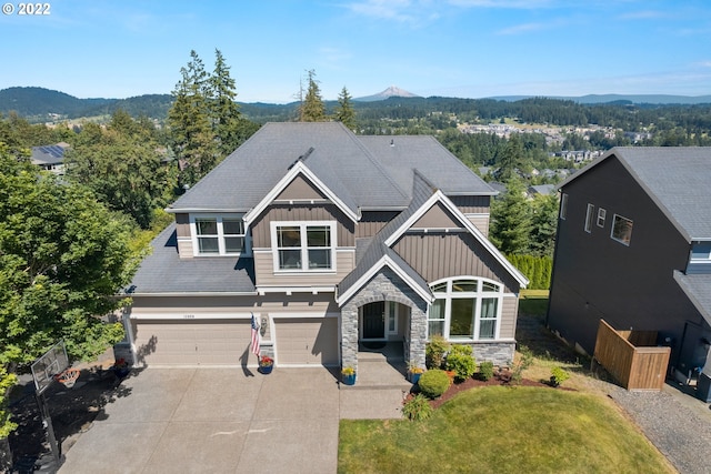 craftsman house featuring board and batten siding, a garage, a mountain view, concrete driveway, and stone siding