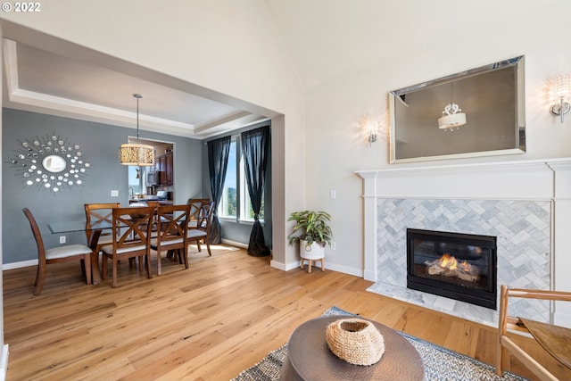living room featuring baseboards, wood finished floors, a raised ceiling, and a tile fireplace