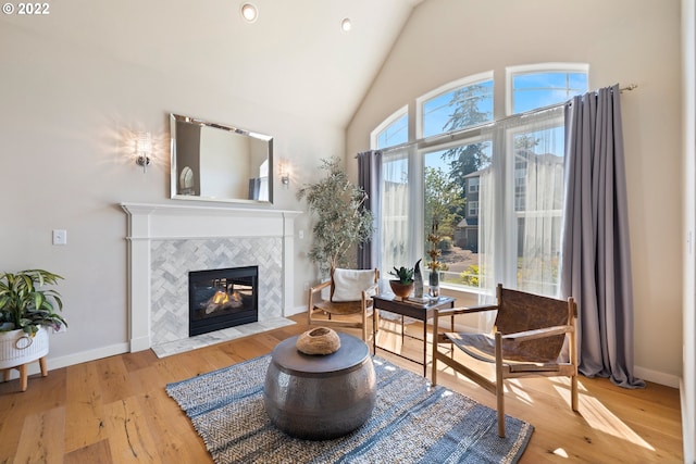 sitting room featuring high vaulted ceiling, hardwood / wood-style floors, recessed lighting, baseboards, and a tile fireplace