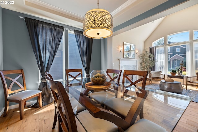 dining space with crown molding, vaulted ceiling, and wood finished floors