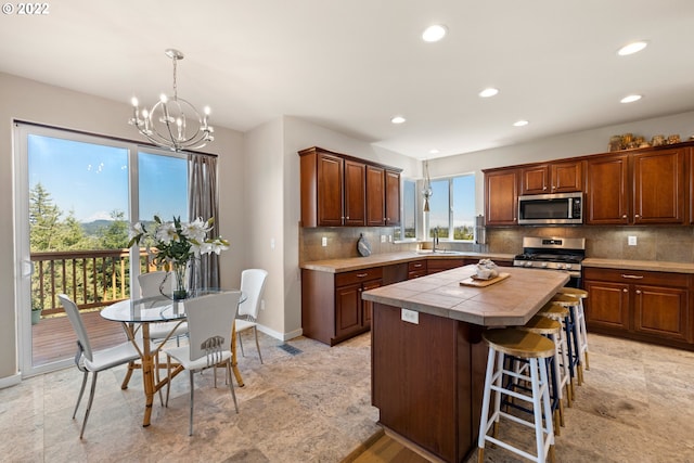 kitchen with decorative backsplash, appliances with stainless steel finishes, a center island, an inviting chandelier, and recessed lighting