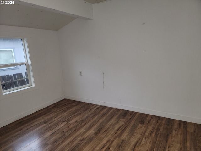 spare room featuring dark wood-type flooring and beamed ceiling