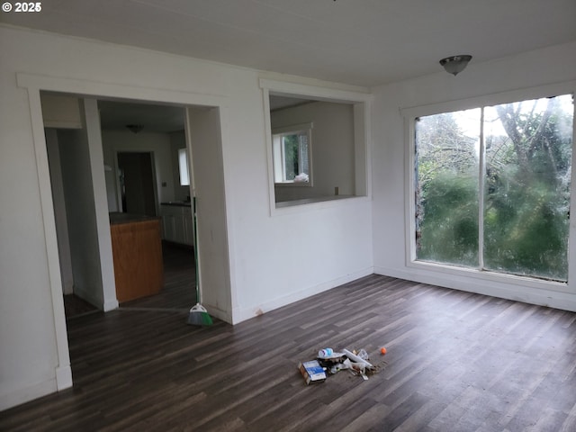 spare room with dark wood-type flooring and a healthy amount of sunlight