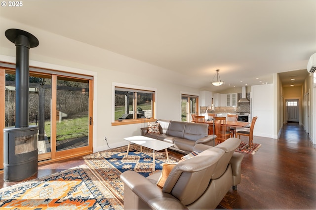 living room featuring a wood stove, plenty of natural light, and a wall unit AC