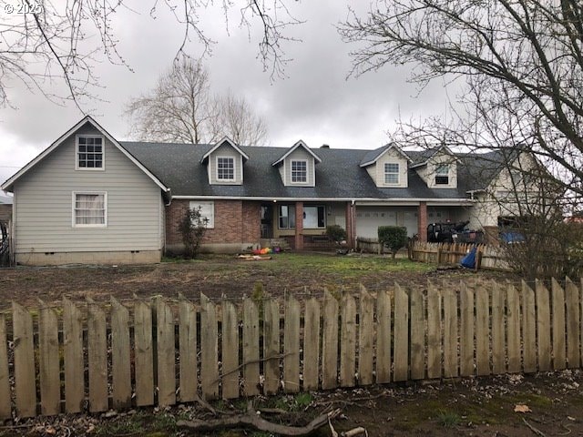 new england style home with a garage, brick siding, crawl space, and fence private yard