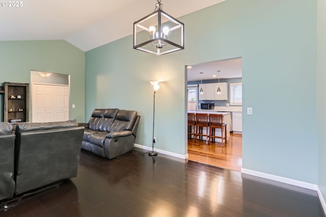 living room with dark wood finished floors, a chandelier, baseboards, and vaulted ceiling