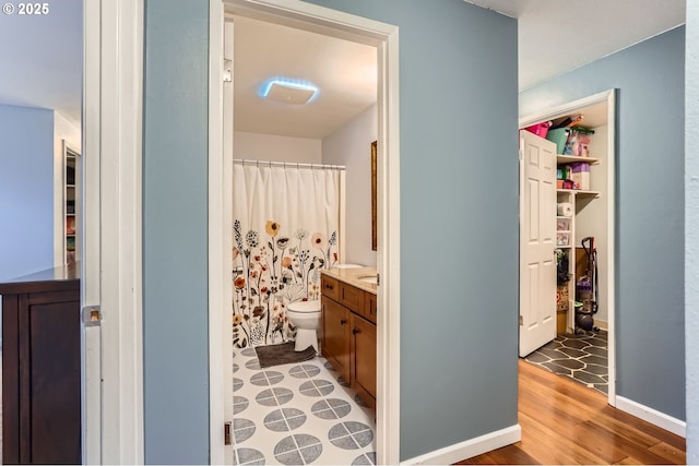 bathroom with vanity, a shower with curtain, wood finished floors, baseboards, and toilet