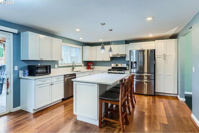 kitchen featuring a sink, under cabinet range hood, dark wood-style floors, white cabinetry, and appliances with stainless steel finishes