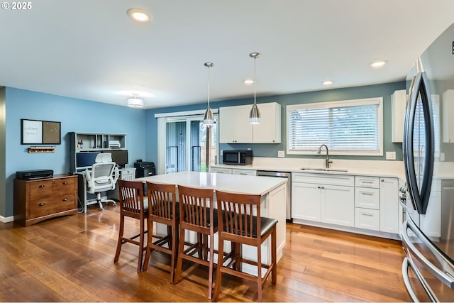 kitchen featuring hardwood / wood-style flooring, white cabinets, stainless steel appliances, and a sink