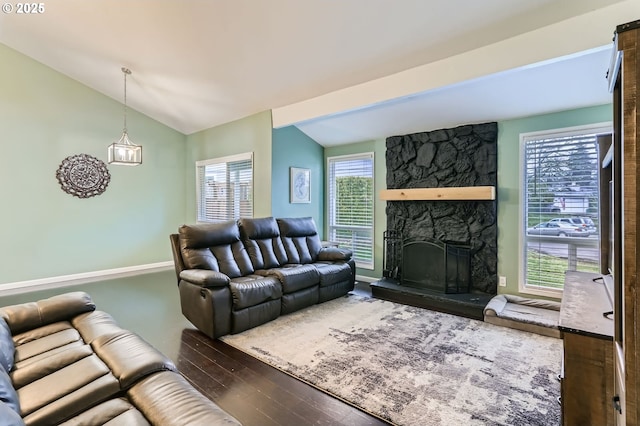 living room featuring lofted ceiling, a stone fireplace, and wood finished floors