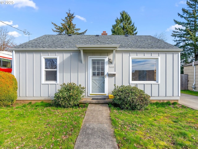 bungalow with a shingled roof, board and batten siding, and a front yard