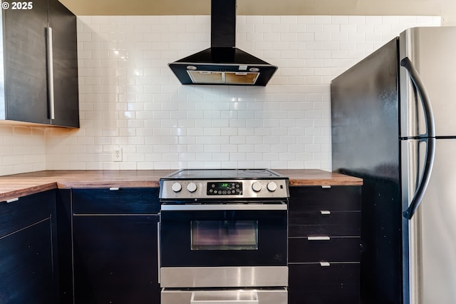 kitchen featuring backsplash, appliances with stainless steel finishes, butcher block countertops, and wall chimney range hood