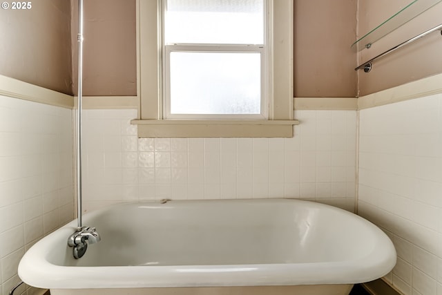 bathroom featuring a washtub and tile walls