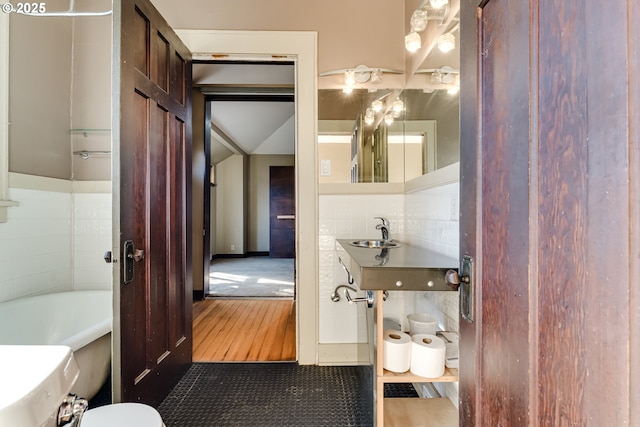 bathroom with sink, tile walls, tasteful backsplash, a bath, and toilet