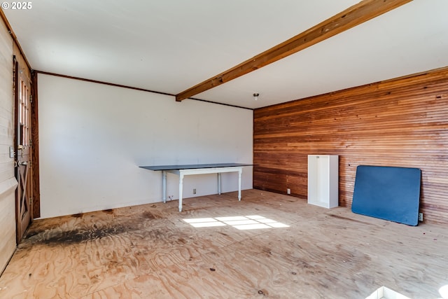 empty room with beamed ceiling and wood walls