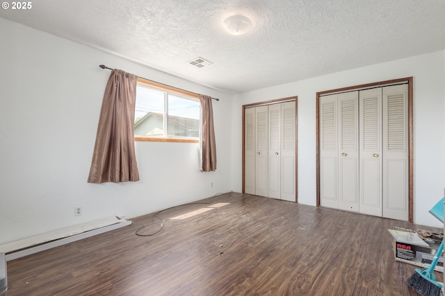 1453 N St, Springfield, OR 97477 - unfurnished bedroom featuring wood finished floors, multiple closets, a textured ceiling, and baseboard heating