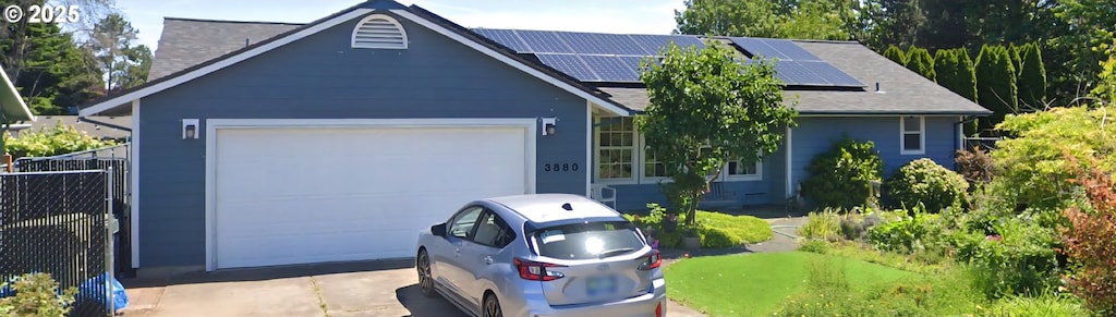 ranch-style house with a garage, concrete driveway, and solar panels