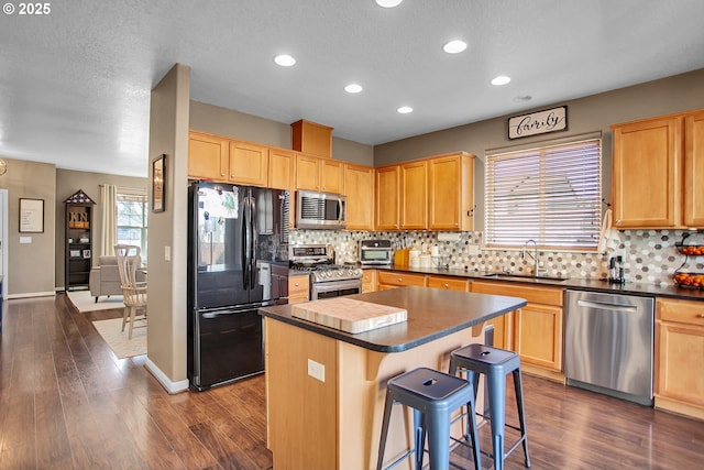 kitchen featuring dark countertops, appliances with stainless steel finishes, backsplash, and a sink