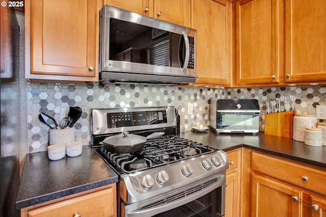 kitchen featuring appliances with stainless steel finishes, dark countertops, and backsplash